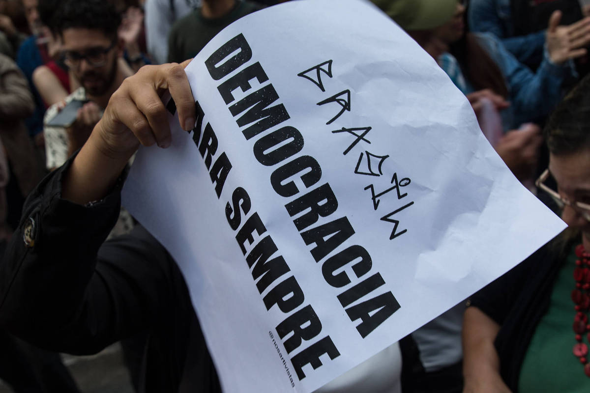 Uma pessoa segurando um cartaz que diz