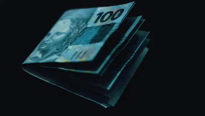 Cédulas de cem reais no fundo preto, são utilizadas para pagar o Imposto de Renda 2025.