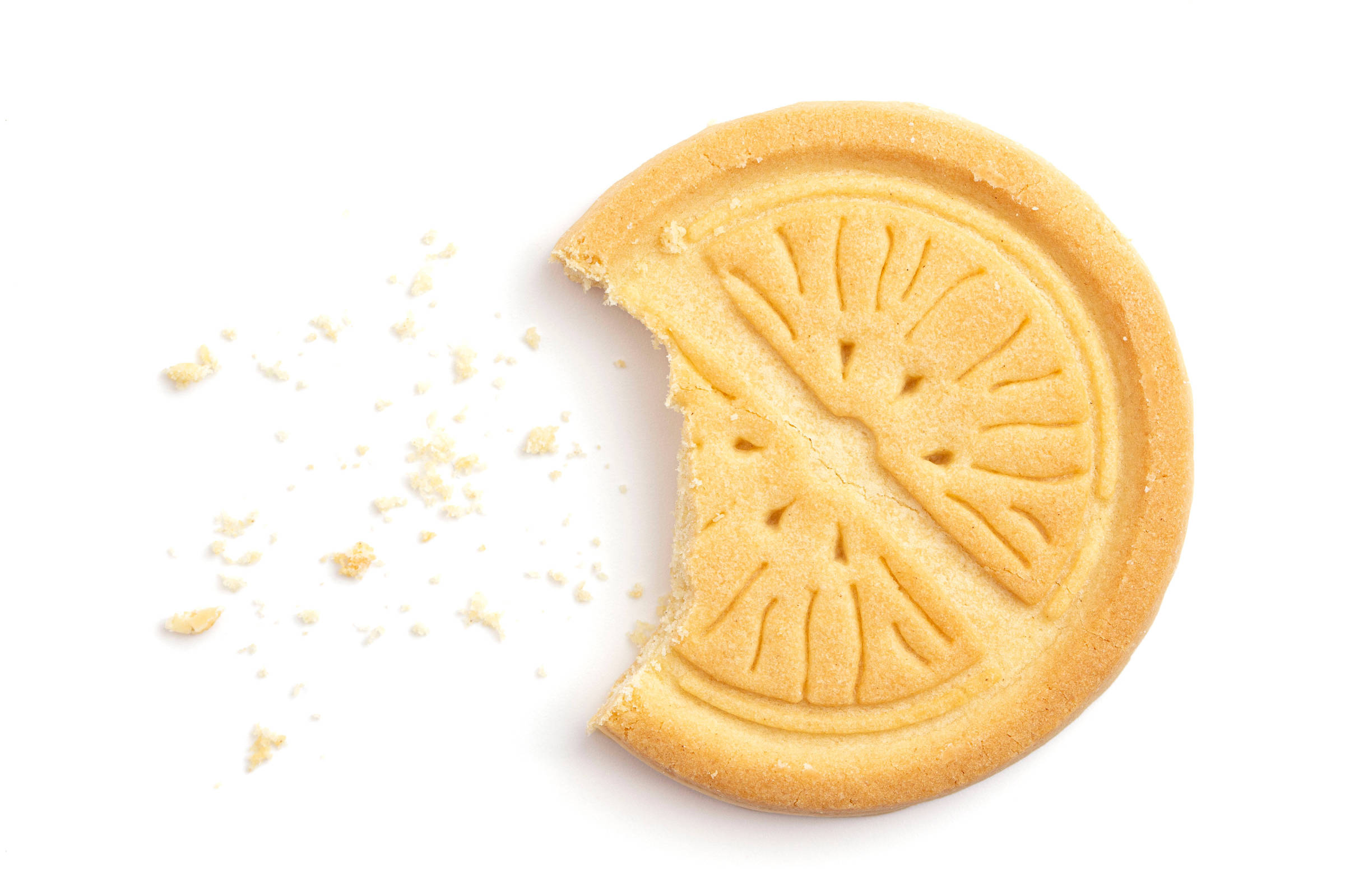 A imagem mostra um biscoito redondo com um pedaço mordido. O biscoito é de cor amarela clara e possui um padrão que lembra uma fatia de limão. Ao lado do biscoito, há algumas migalhas espalhadas.
