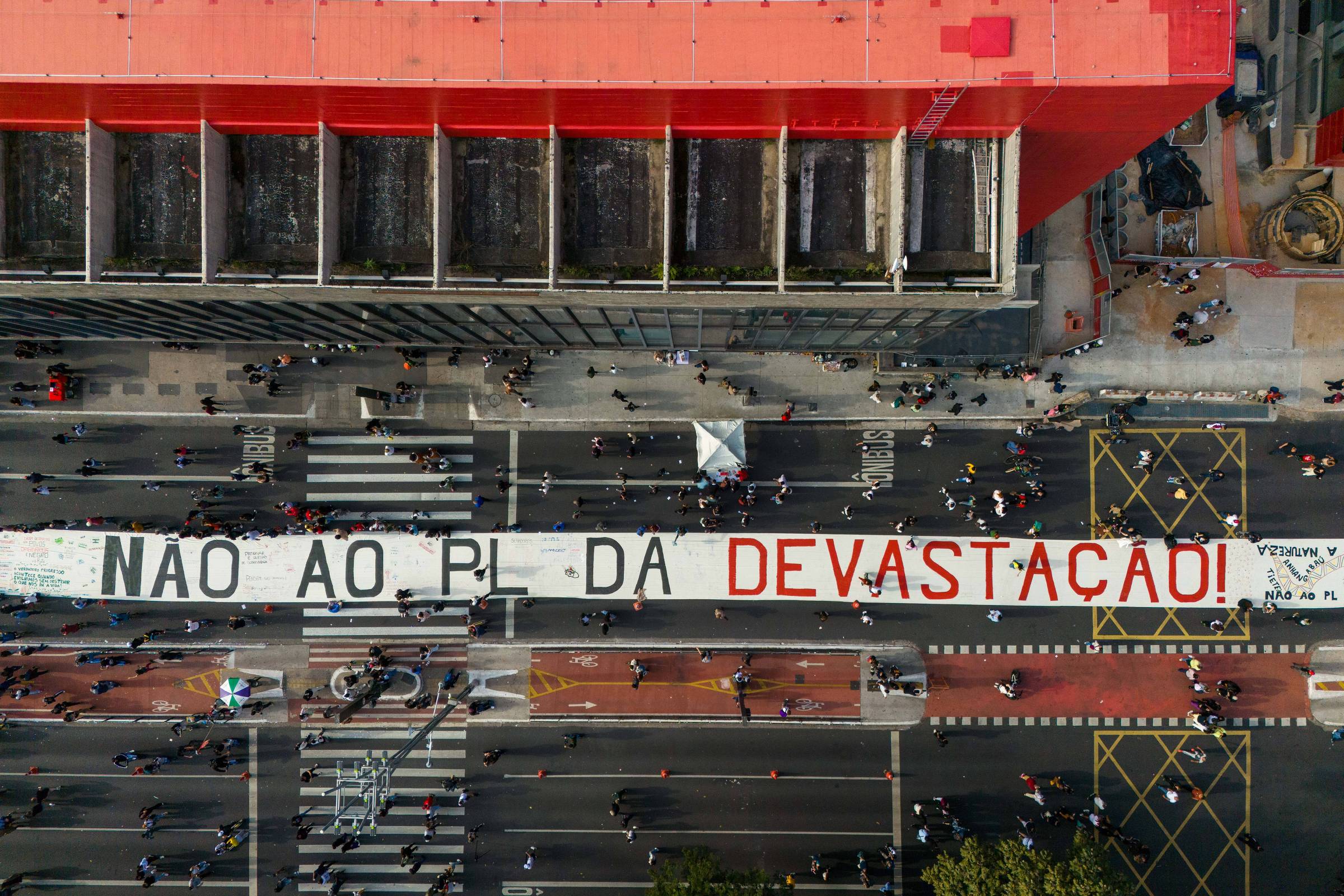 A imagem mostra uma grande faixa estendida sobre uma rua, com a inscrição em letras grandes: