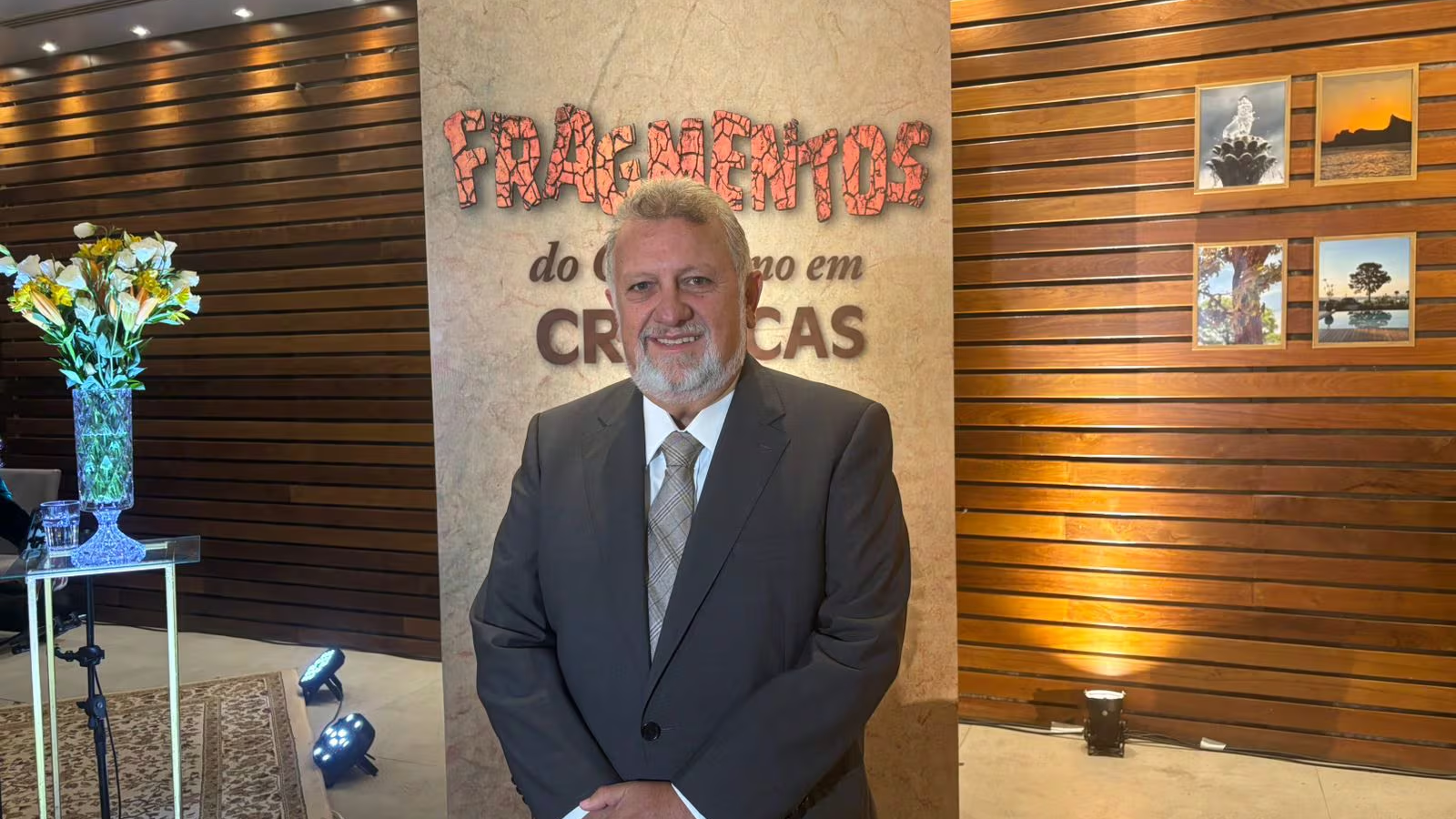 Autor durante o lançamento do livro Fragmentos do Cotidiano em Crônicas, em ambiente interno, posando diante do painel do evento