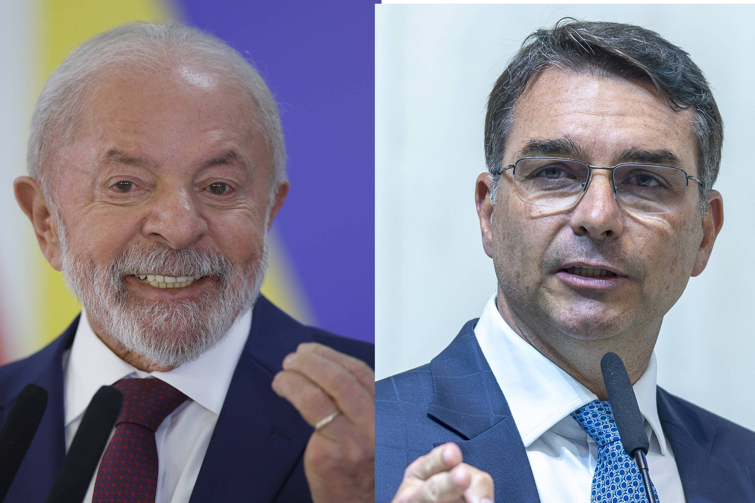 Dois homens em trajes formais falam em microfones. O homem à esquerda tem cabelo e barba grisalhos, veste terno escuro com gravata vermelha e sorri. O homem à direita usa óculos, terno azul e gravata azul clara, e gesticula com a mão direita.