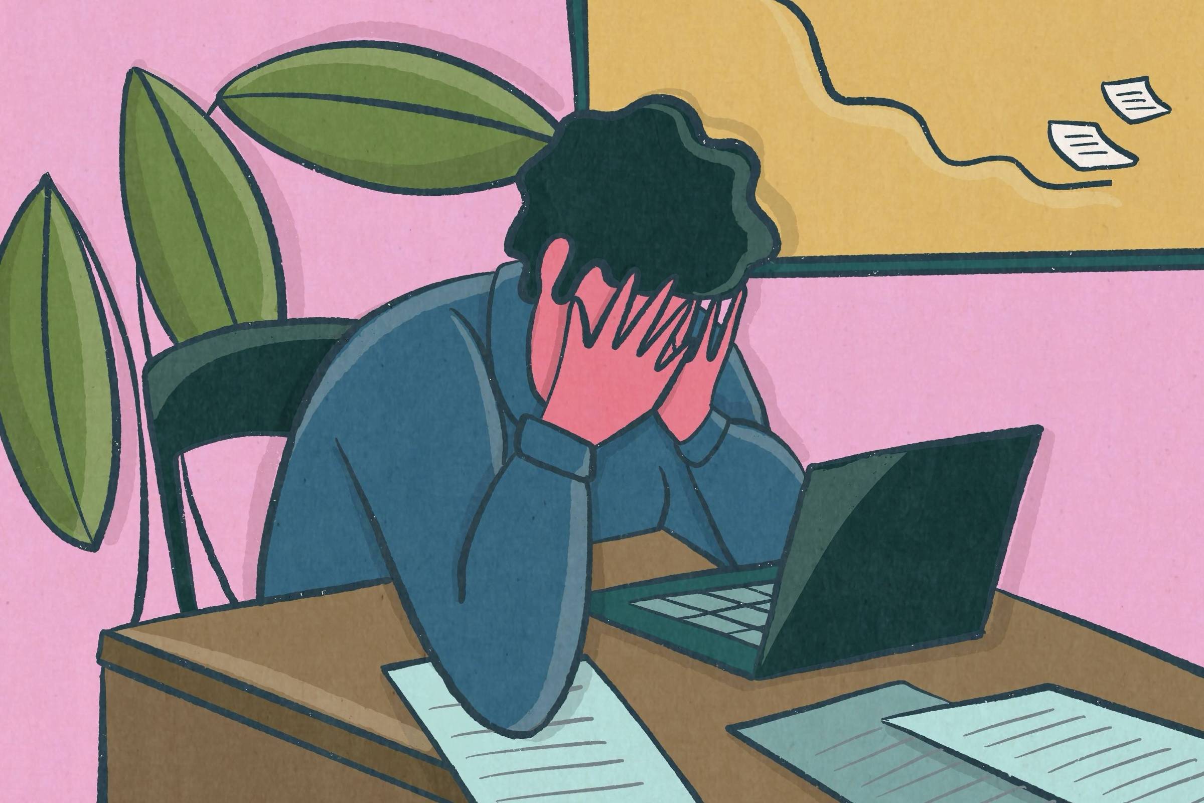 Pessoa sentada em cadeira preta, com as mãos cobrindo o rosto, diante de laptop aberto sobre mesa de madeira. Documentos espalhados na mesa e quadro de avisos amarelo ao fundo com papéis presos. Paredes cor de rosa e plantas verdes ao lado.