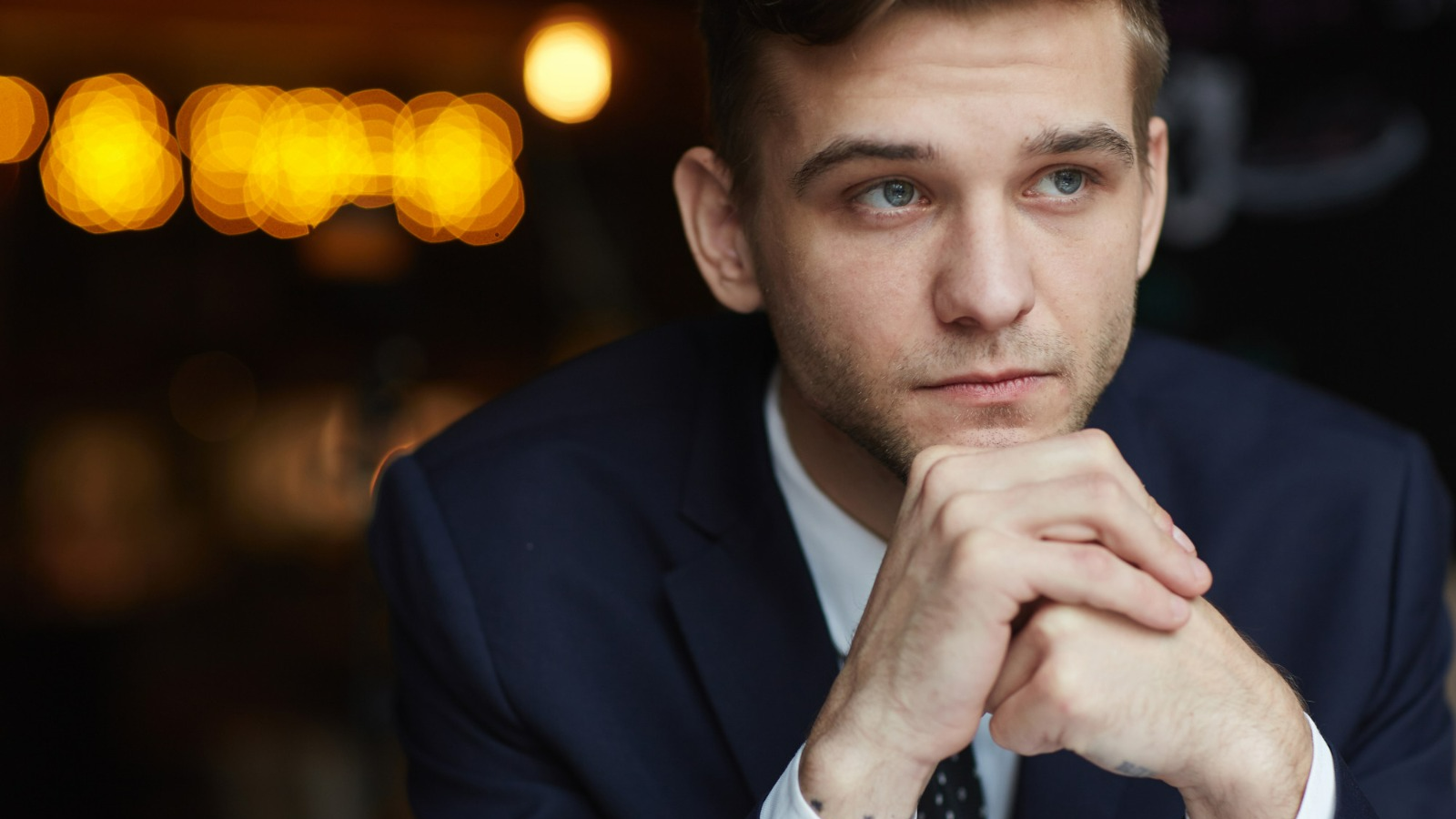 Profissional em momento de reflexão, com expressão séria e olhar distante, representando tomada de decisão e conflito interno na carreira