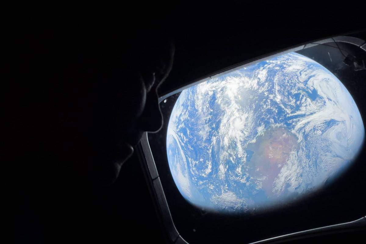 Planeta Terra visível através da janela de uma nave espacial, mostrando nuvens e oceanos. Silhueta de uma pessoa observando a vista no lado esquerdo da imagem.